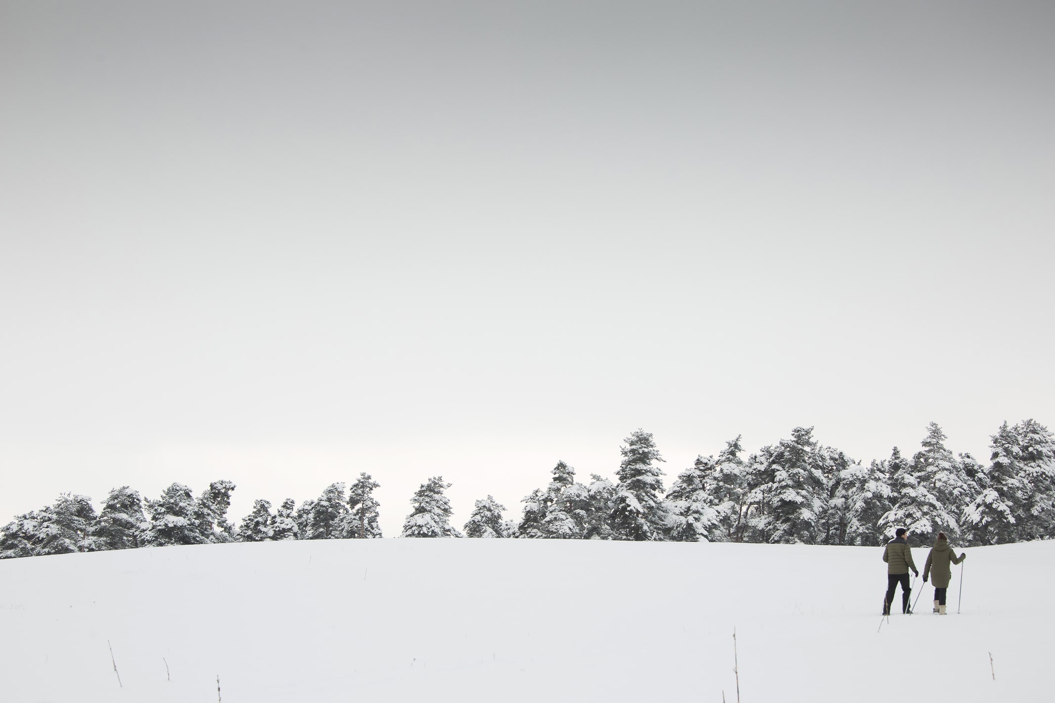 Couple snowshoeing in the vast, snowy landscapes of the Cantal, French Highlands. Clean air and great escape at instants d'Absolu.