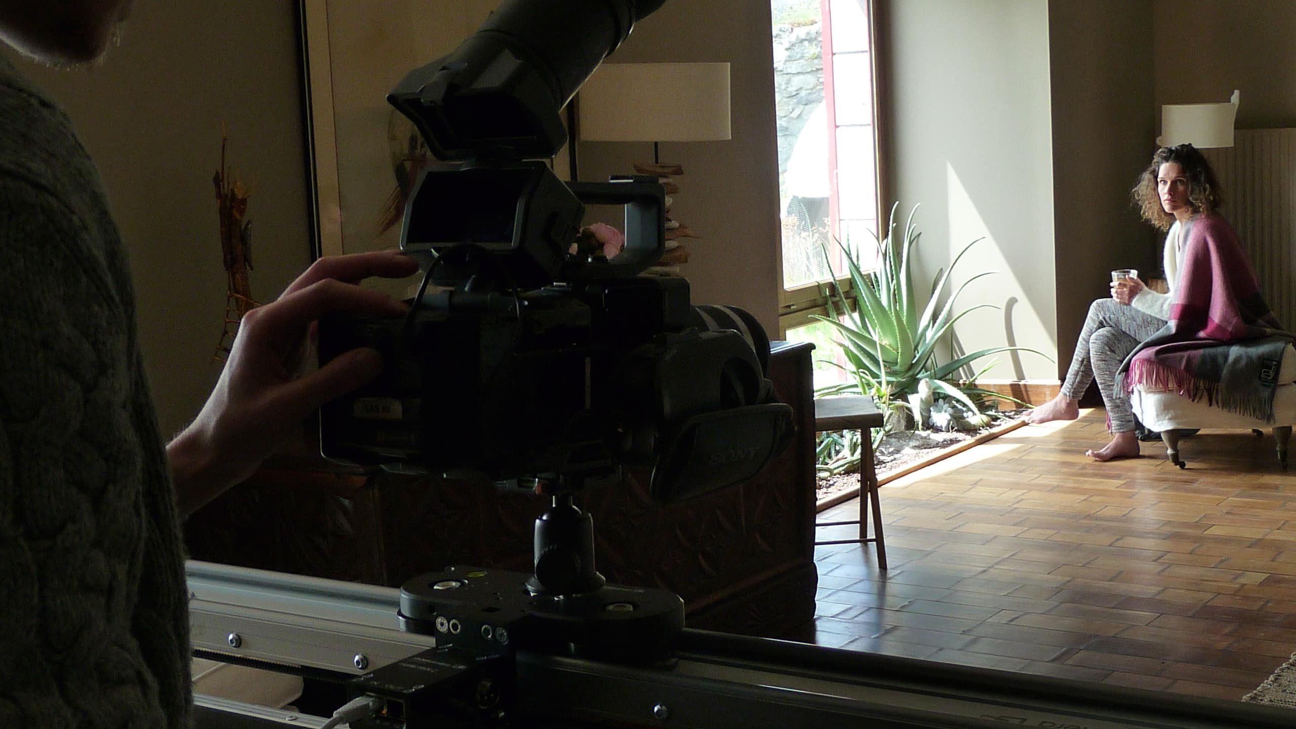 Behind-the-scenes filming at the Cantal ecolodge: close-up on the camera and person seated wrapped in a blanket.
