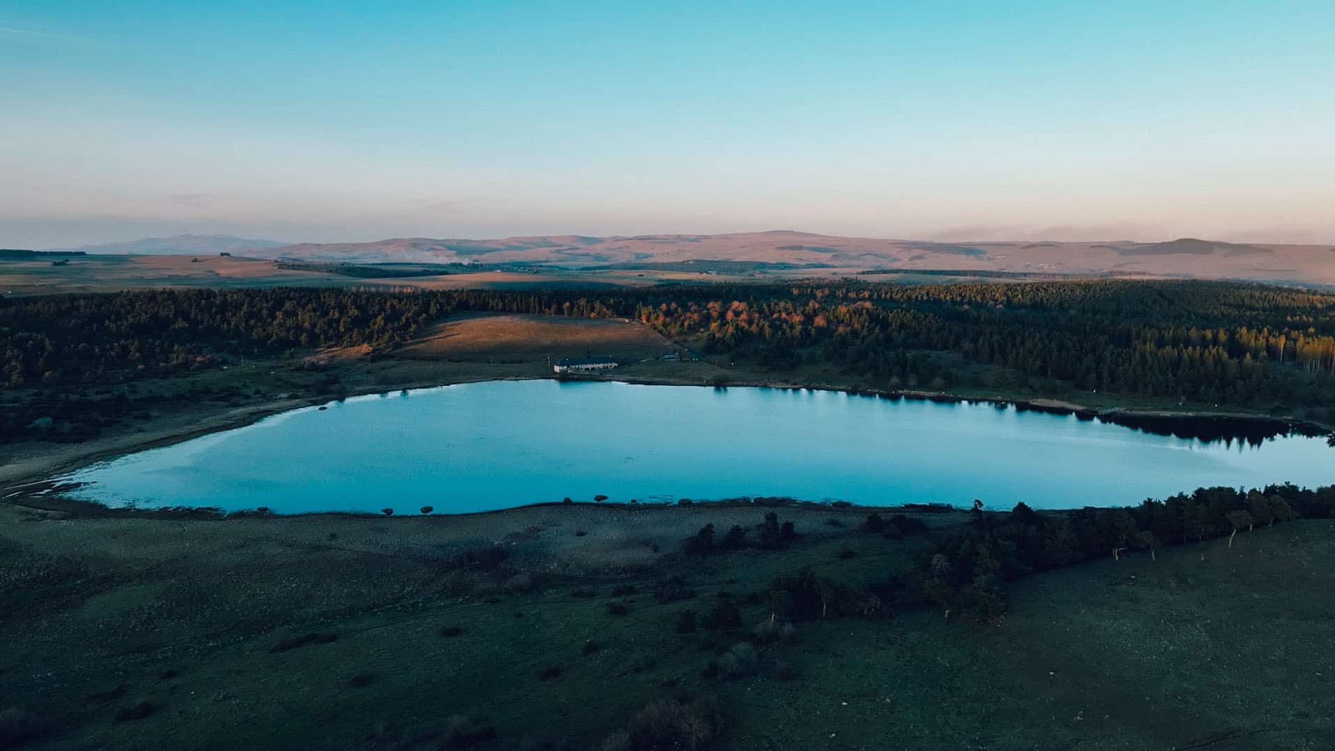 A panoramic view of Lac du Pêcher in Auvergne at sunrise, capturing the luxury of emptiness.