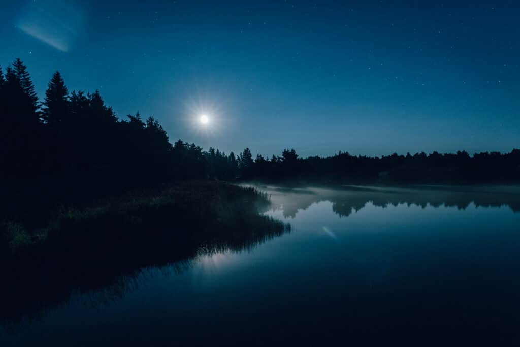 Night photo of instants d'Absolu - Ecolodge & Spa in Cantal, under stars and mist, with reflection on the lake. Image captured by L'Œil d'Eos for the CGS Zero Number call.