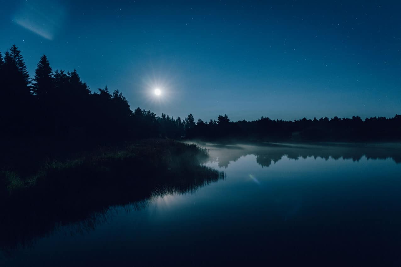 Photo nocturne d'instants d'Absolu - Ecolodge & Spa réservant une dynamique de séjour Cantal Grand Spectacle sous les étoiles et la brume, avec reflet sur le lac. Image réalisée par L'Œil d'Eos pour l'appel Numéro Zéro.