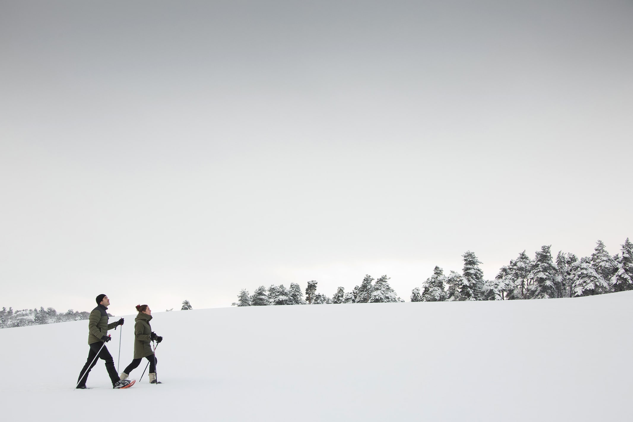 Couple en raquettes dans les paysages enneigés du Cantal. Grands espaces et air pur depuis l'écolodge instants d'Absolu.